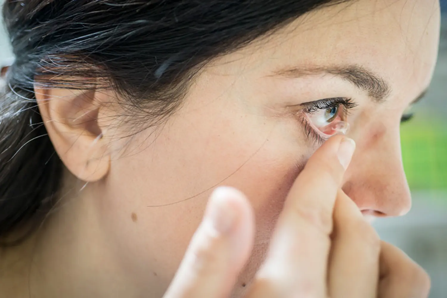 Eine Frau, die sich Linsen in die Augen setzt von Augenoptik Klöter