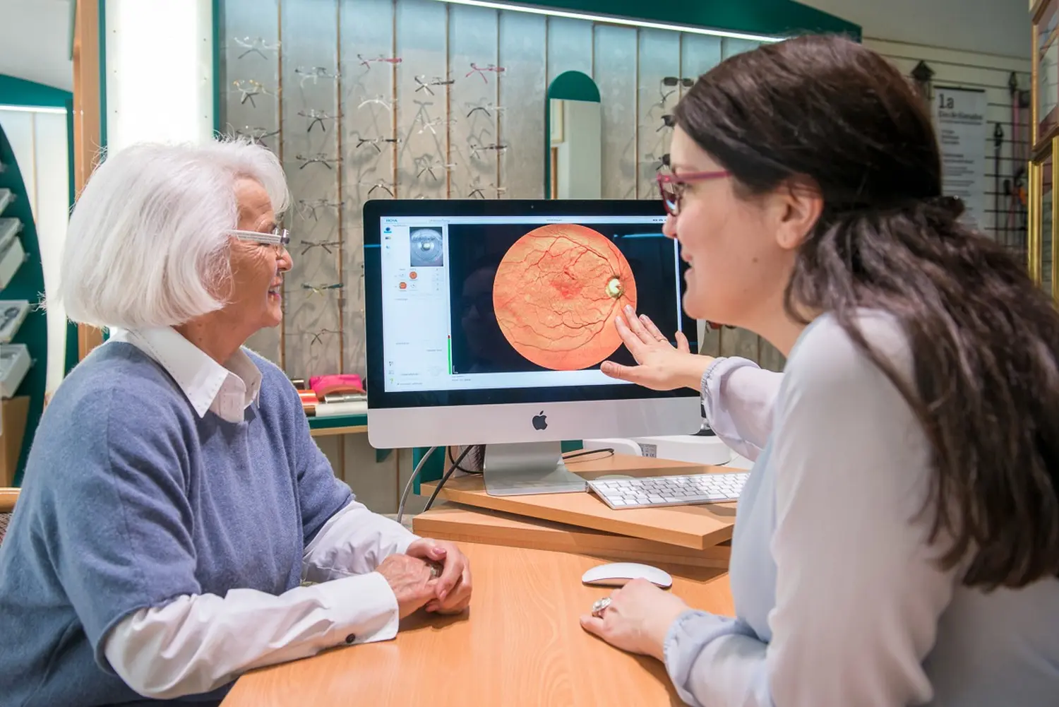 Ein Optiker erklärt einem Patienten von Augenoptik Klöter die Ergebnisse einer Netzhautuntersuchung