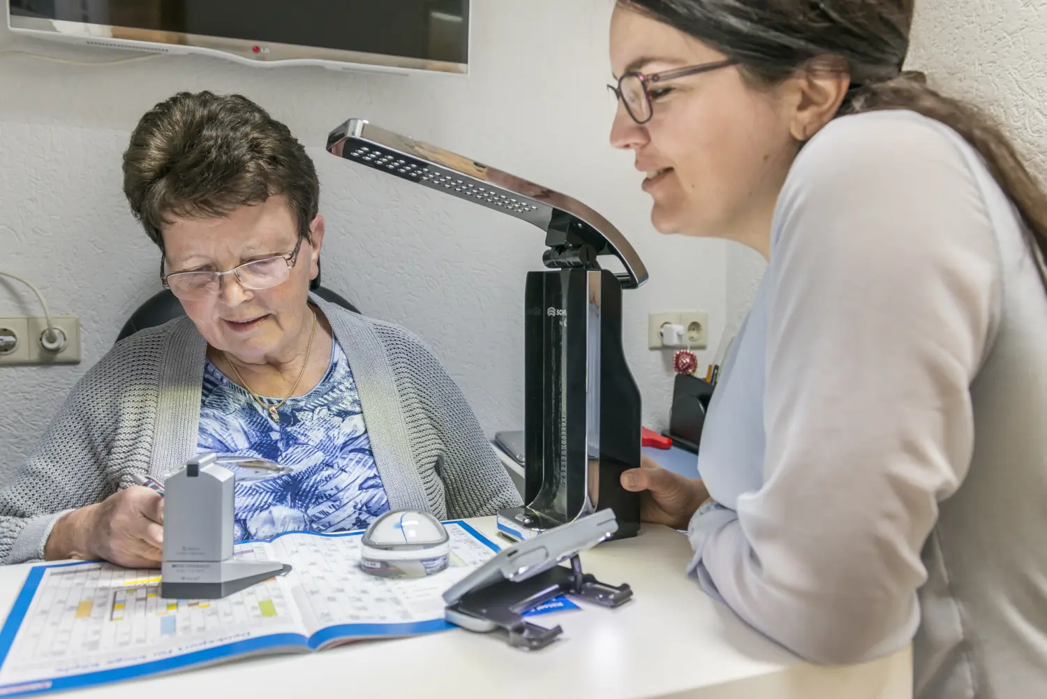 Ein Optiker erklärt einem Patienten von Augenoptik Klöter die Ergebnisse einer Netzhautuntersuchung